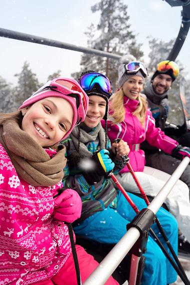 Eine Familie sitzt in einem Skilift und machen ein Selfie. 